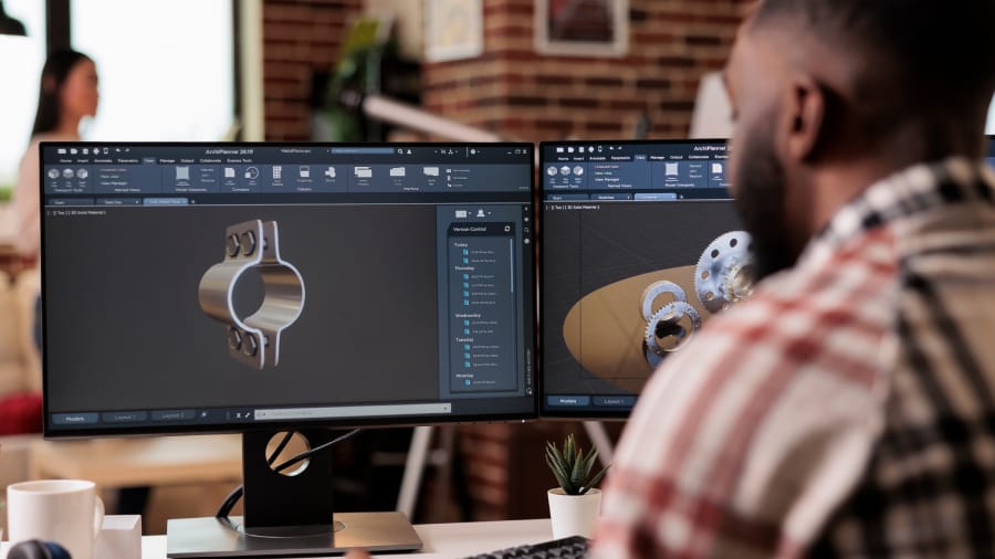 3D design technician creating 3D CAD models of mechanical parts on dual monitors for 3D printing services in St Catharines, Ontario.